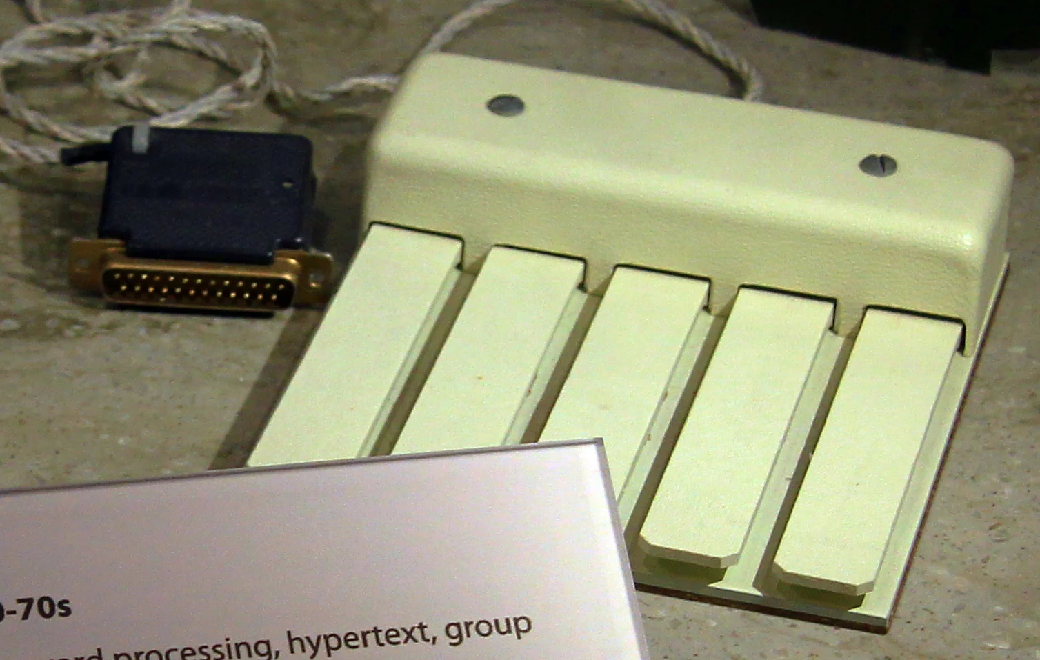 Close view of the five-key chord keyset: five long pale keys in a row on a moulded body, its cable ending in a gold connector.