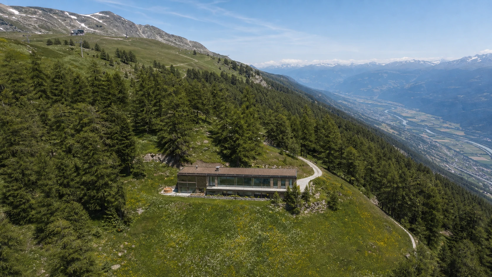 Plans-Mayens from the air in late June, the chalet ringed by larch and stone pine.