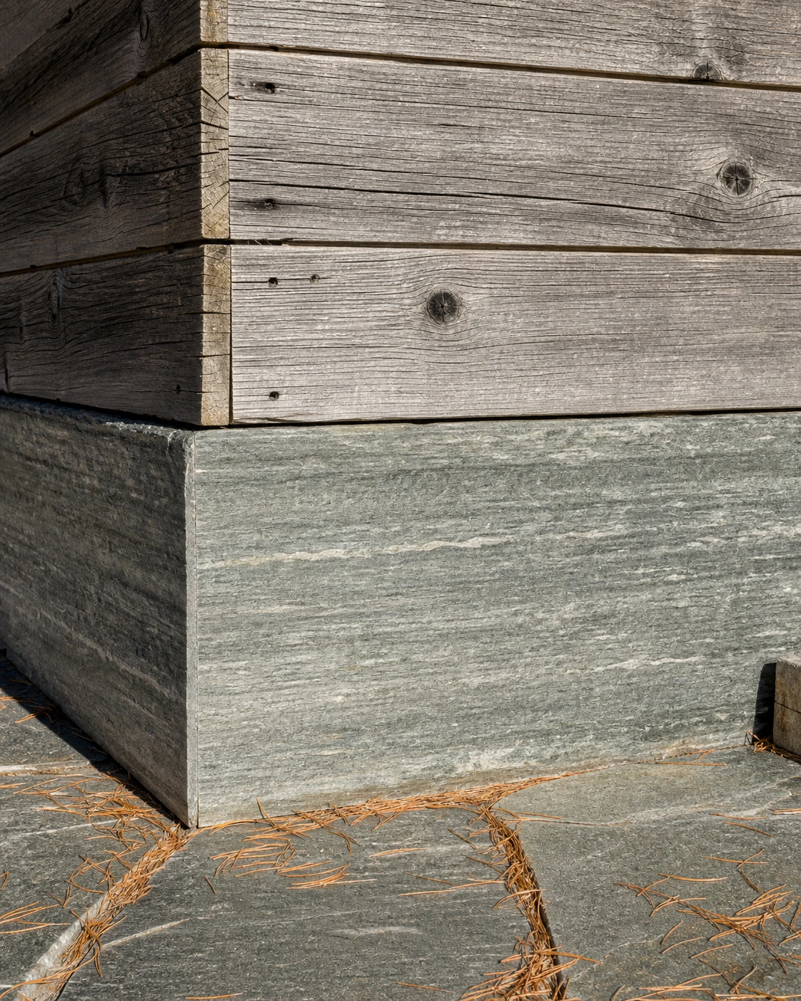Weathered Anniviers larch cladding meeting the brushed Vals quartzite plinth.